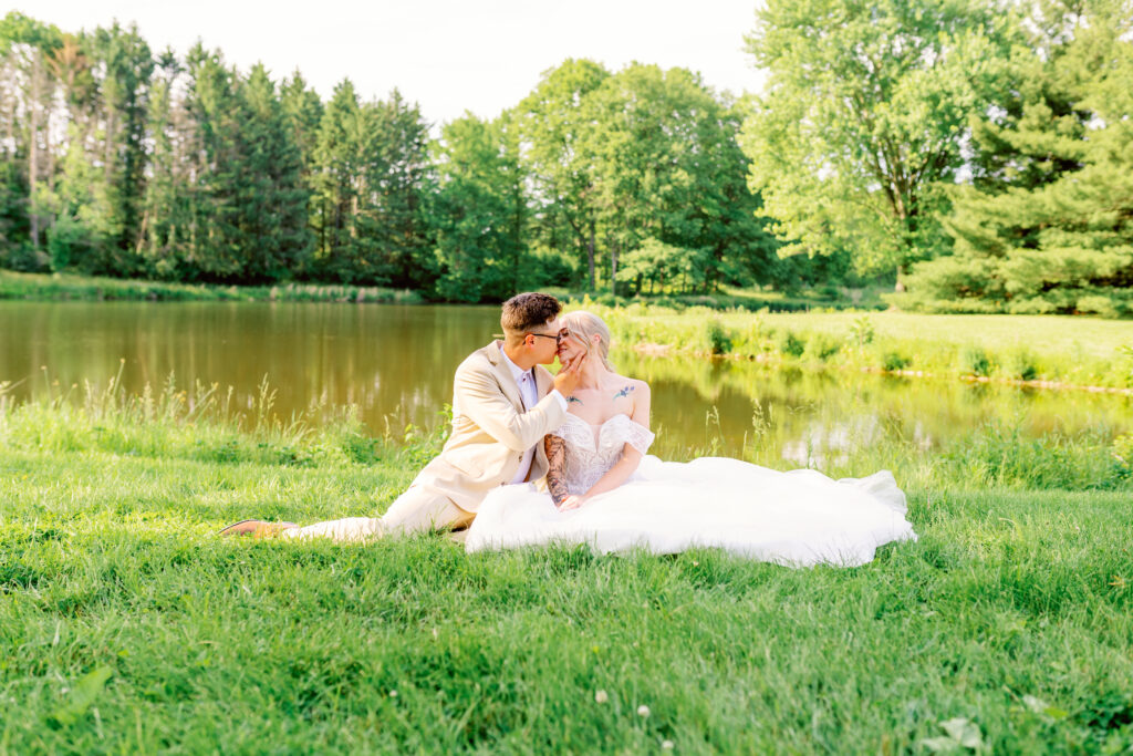 Bride and groom sitting by a lake 
