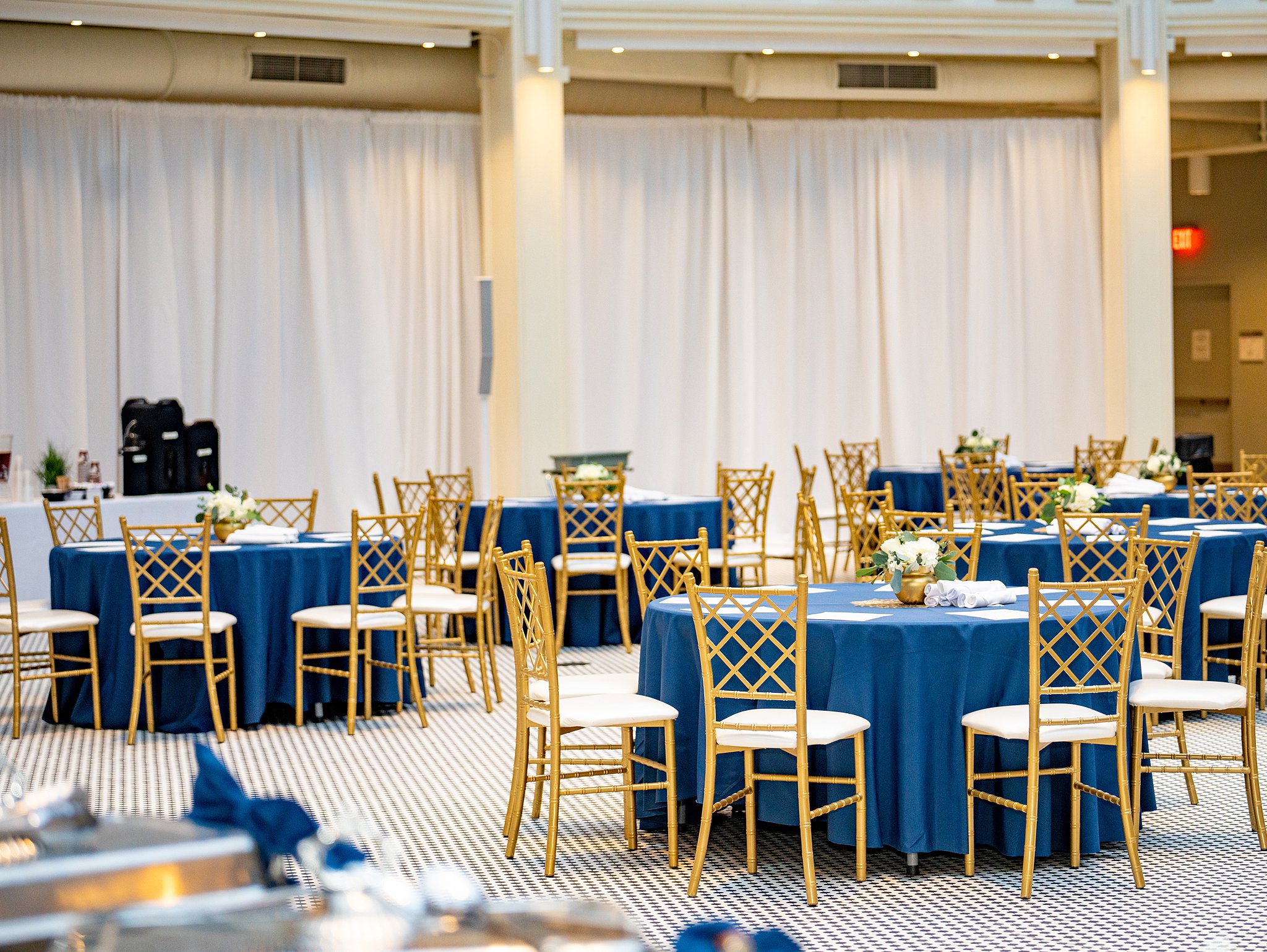 wedding reception setup with blue linen and gold chairs