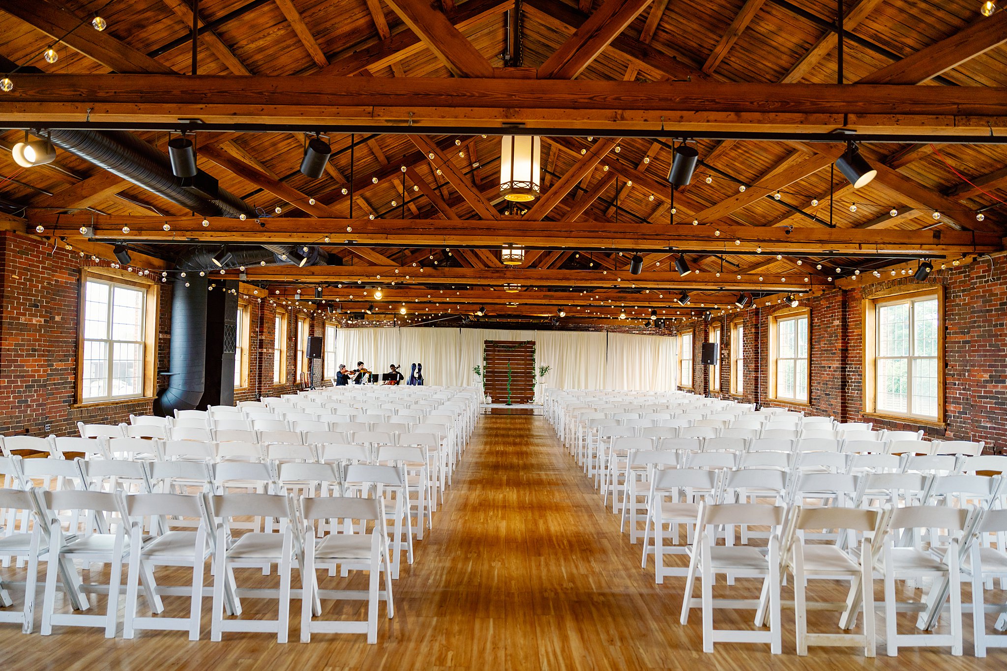 A large barn setup for a wedding ceremony with market lights and white chairs unique wedding venues dayton ohio
